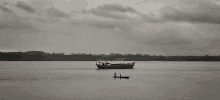 a black and white photo of two people in a small boat in the water