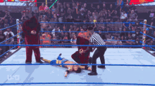 a wrestler is laying on the ground in a wrestling ring with a referee