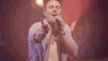a man is singing into a microphone on a stage in a blurry photo .