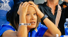 a woman wearing a blue shirt with the word cowboys on it holds her head