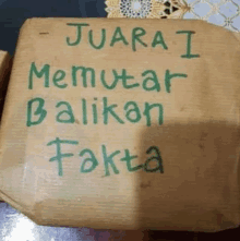 a piece of brown paper with green writing that says juara i memutar balikan fakta