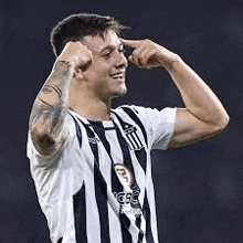 a man in a striped soccer jersey is flexing his muscles and smiling .