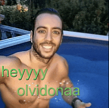 a shirtless man is swimming in a pool with the words heyyyy olvidonaa written on his chest