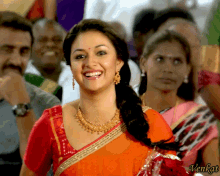 a woman in an orange saree smiles in front of a group of people with the name venkat on the bottom