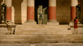 a man in a red robe is standing on the steps of a building
