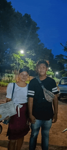 a man and a woman standing next to each other in a park at night