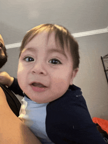 a man holds a baby in his arms and the baby is wearing a blue shirt that says columbia