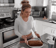 a woman is cutting a loaf of bread in a kitchen with a sign that says ' agility ' on it