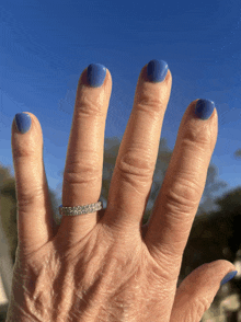 a close up of a woman 's hand with blue nails and a ring