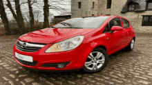 a red car is parked on a cobblestone driveway