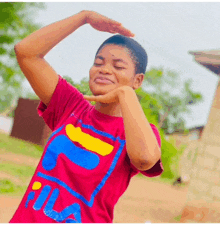 a woman wearing a red fila t-shirt is making a heart with her hands