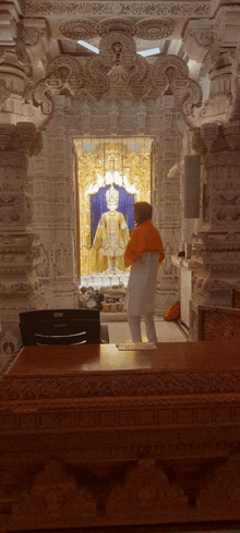 a man in an orange shirt is standing in front of a statue