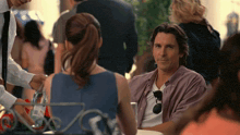 a man in a purple shirt sits at a table talking to a woman