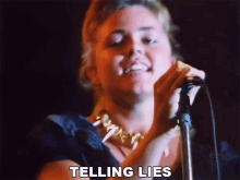 a woman singing into a microphone with the words " telling lies " below her