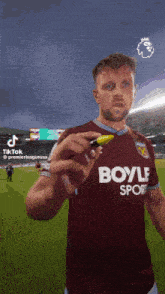 a man in a boyle sport jersey holds a marker