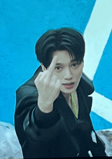 a young man is giving the middle finger in front of a blue background