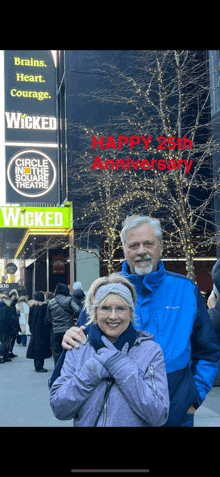 a man and woman standing in front of a sign that says happy 25th anniversary