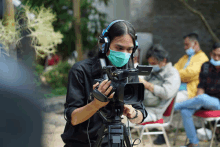 a man wearing a mask and headphones is holding a camera that says sony on it