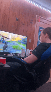 a man sits in a chair in front of a television playing a video game