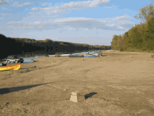 a yellow canoe with the word kayak on it sits on a sandy beach near a river