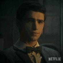 a man in a suit and bow tie is sitting in front of a netflix sign .