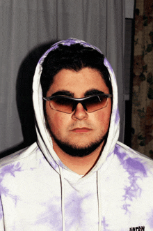 a man wearing sunglasses and a purple tie dye hoodie with the word hunter on it