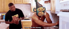 a shirtless man in a party hat is standing in a kitchen next to a man holding a football and a monkey .