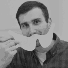 a man wearing a plaid shirt is holding a paper mask in front of his face