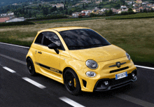 a yellow abarth car driving down a road