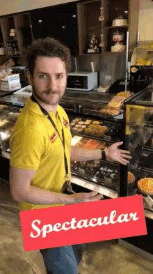 a man in a yellow shirt is standing in front of a display case and a sign that says spectacular