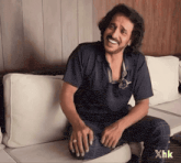 a man is sitting on a couch with the letters xhk on the bottom