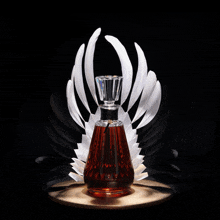 a bottle of cognac is surrounded by feathers on a black background