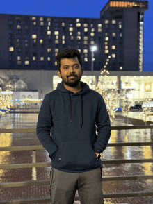 a man in a blue hoodie stands in front of a building