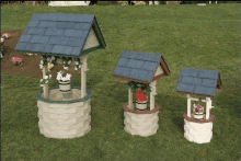 three wooden wishing wells are sitting on top of a lush green field .