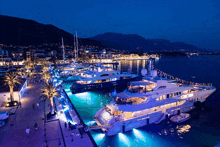 several boats are docked in a harbor at night and one of them has the word yacht on its side