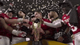 a group of football players are holding a trophy and one of them has the number 25 on his shirt