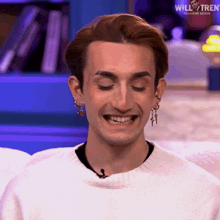 a man wearing a white sweater and earrings is smiling with the words will & tren on the bottom