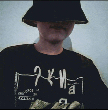 a person wearing a bucket hat and a shirt that says 2k11 covering their face