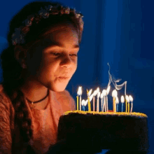 a little girl is blowing out candles on her birthday cake .