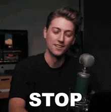 a man is standing in front of a microphone with the word stop written on his face .