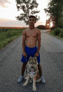 a shirtless man in blue shorts is standing next to a dog on a leash