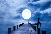 a person is sitting on a pier fishing at night .