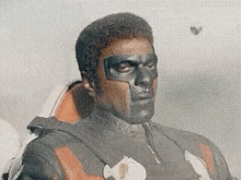 a man with black paint on his face is wearing a superhero costume and mask .