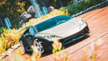 a lamborghini is driving down a dirt road in a video game