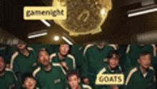 a group of people wearing green shirts with the word goats on them are standing in a room .