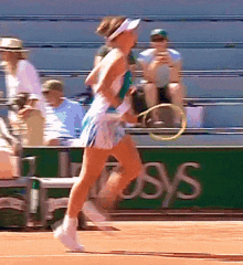 a woman is running with a tennis racquet on a tennis court in front of a sign that says ' osys '