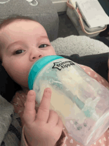 a baby drinking from a tomme tippee bottle