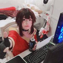 a girl sitting at a desk holding a can of monster energy drink