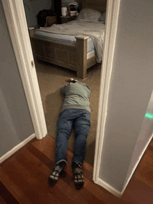 a person is laying on the floor in a bedroom with a bed in the background