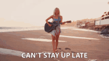 a woman playing a guitar on the beach with the words " can 't stay up late " above her